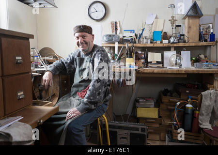 Senior orafo maschio sorridente in officina, Baviera, Germania Foto Stock