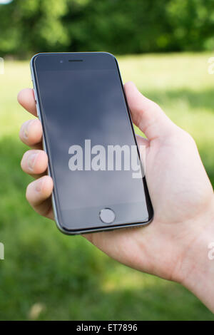 Stretta di mano d'uomo tenendo uno smartphone Foto Stock