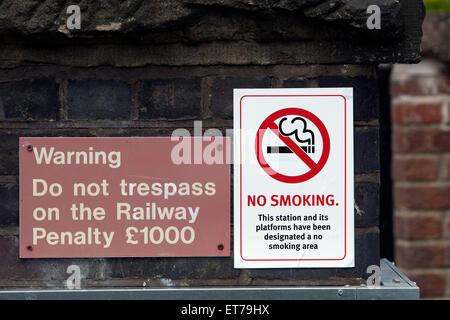 Non fumare e sconfinamenti di segni su una stazione ferroviaria, Warwickshire, Regno Unito Foto Stock