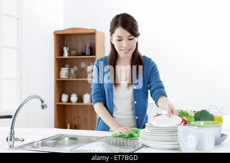 Giovane donna che guarda verso il basso e piastre di lavaggio Foto Stock