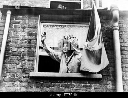 Un Suffragette inclinazione verso l'esterno di una finestra, gesticolando e tenendo un banner. Circa 1912. Foto Stock