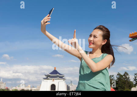 Giovane donna di scattare le foto con smart phone e sorridente Foto Stock