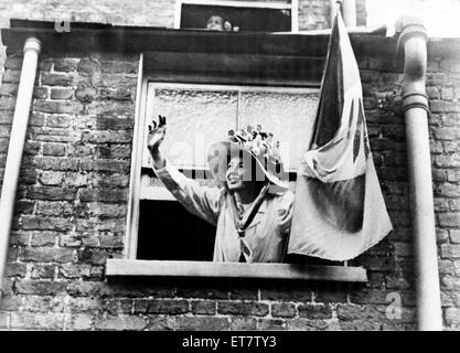 Un Suffragette inclinazione verso l'esterno di una finestra, gesticolando e tenendo un banner. Circa 1912. Foto Stock