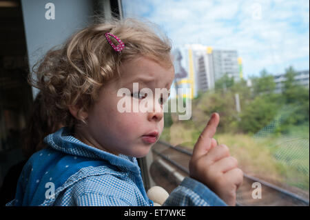 Berlino, Germania, una bambina guarda mentre cavalcate il treno fuori della finestra Foto Stock