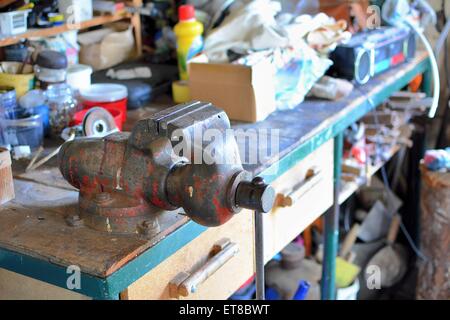 Tabella disordinato con il vecchio metallo arrugginito vice e gli altri strumenti di lavoro in officina. Foto Stock