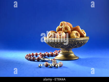 Una ciotola ornamentale di datteri con perline di rosario islamico. Oggetti e sfondo del Santo Ramadan. Foto Stock