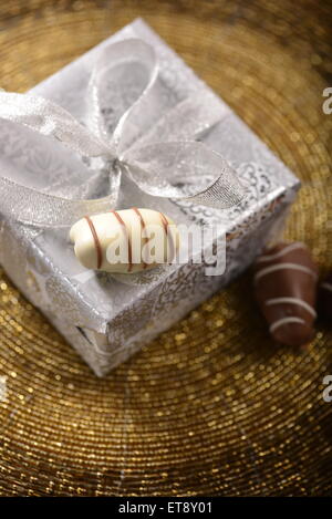Un argento Confezione regalo e tre data la frutta cioccolatini da angolo superiore. Foto Stock