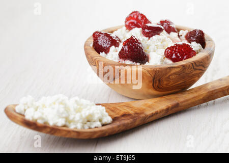 Formaggio con conserva di fragola in ciotola di legno su tavola in legno di quercia Foto Stock