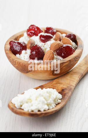 Formaggio con conserva di fragola in ciotola di legno su tavola in legno di quercia Foto Stock