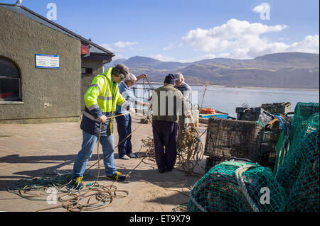 I pescatori tentare di districare un sacco di corde sulla banchina sotto il sole con le montagne di cader Idris in background. Foto Stock