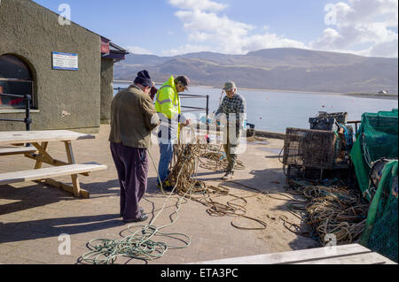 I pescatori tentare di districare un sacco di corde sulla banchina sotto il sole con le montagne di cader Idris in background. Foto Stock