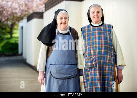 Due suore cistercensi indossando grembiuli di lavoro a Santa Croce abbazia vicino Whitland, Pembrokeshire Wales, Regno Unito Foto Stock