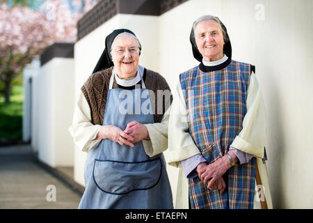 Due suore cistercensi indossando grembiuli di lavoro a Santa Croce abbazia vicino Whitland, Pembrokeshire Wales, Regno Unito Foto Stock