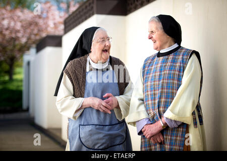 Due suore cistercensi indossando grembiuli di lavoro a Santa Croce abbazia vicino Whitland, Pembrokeshire Wales, Regno Unito Foto Stock