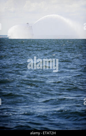 Un fireboat spruzza acqua in aria durante un trapano di mare Foto Stock