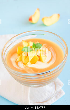 Peach dessert (mousse) con yogurt e menta su sfondo blu Foto Stock