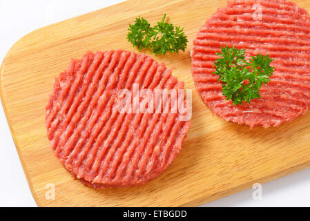 Due materie hamburger polpette con il prezzemolo sul tagliere di legno Foto Stock