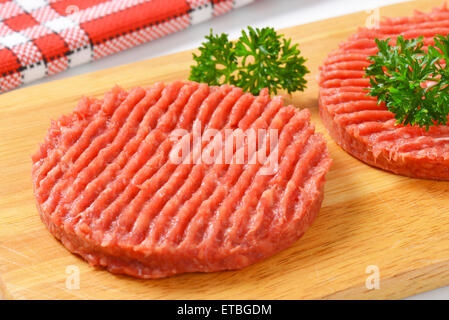 Dettaglio delle due materie hamburger polpette con il prezzemolo sul tagliere di legno Foto Stock