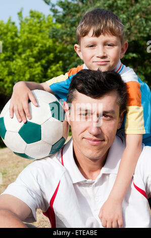 Il padre e il figlio è venuto al parco a giocare a calcio e scattare una foto Foto Stock