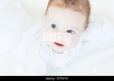 Sweet Baby girl con bellissimi occhi azzurri Succhiare le dita Foto Stock