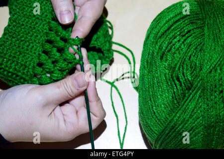 Donna crotching lana di un cappello verde su un tavolo Foto Stock