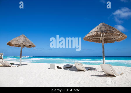 Mar dei Caraibi costa con erba Ombrelloni in legno e lettini da spiaggia. Concetto di vacanza Foto Stock