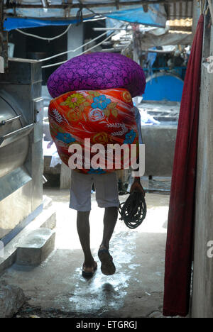 L'uomo la sacca di custodia di lavaggio di vestiti a Mahalaxmi Dhobi Ghat aperto lavanderia a gettoni, Mumbai, Maharashtra, India. Foto Stock