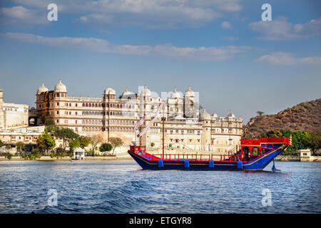 Barca sul Lago Pichola con City Palace vista sul cielo blu in Udaipur, Rajasthan, India Foto Stock