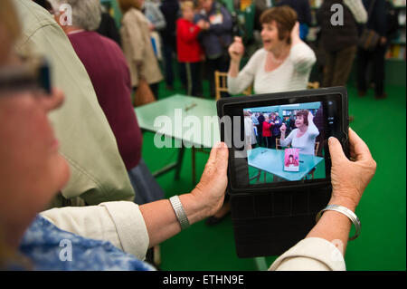 Pam Ayers poeta e autore libro firma mentre viene girato su un computer tablet con ventole in libreria a Hay Festival 2015 Foto Stock