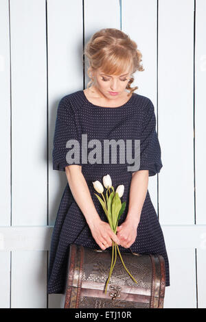 Bella Donna con fiori in mano e una valigia Foto Stock