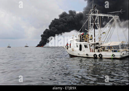 Nuvole scure riempiono il cielo come gamberetti è utilizzare un braccio per raccogliere il petrolio greggio durante una superficie controllata masterizzare a seguito della BP Deepwater Horizon oil spill disastro come gli sforzi per contenere e pulire i milioni di galloni di equipaggio continuare il 6 maggio 2010 nel Golfo del Messico. Foto Stock