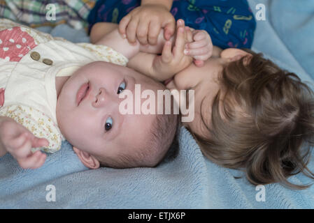 Un bambino di 2 anni un ragazzo e sua sorella neonato sdraiato su un lettino. Foto Stock