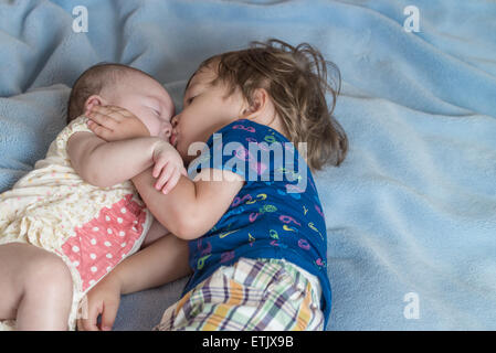 Un bambino di 2 anni un ragazzo e sua sorella neonato sdraiato su un lettino. Foto Stock