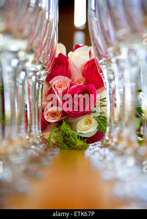 Una disposizione di bicchieri di champagne e un bouquet nuziale con rose Foto Stock