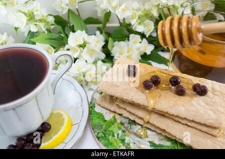 Una sana colazione con biscotti integrali miele e tè chokeberry Foto Stock