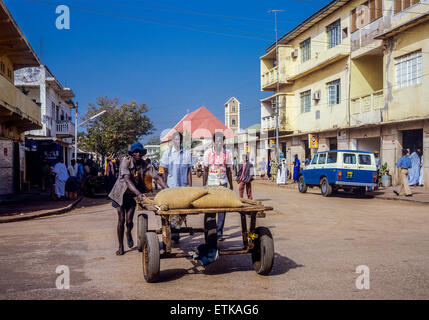 Tre uomini gambiana con consegna carrello caricate con sacchetti, Banjul (Gambia, Africa occidentale Foto Stock