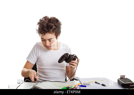 Ragazzo caucasica nel manicotto corto t-shirt gioca con un controller di gioco seduti di fronte la sua casa sulla scrivania Foto Stock