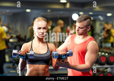 Coppia giovane con manubri flettendo i muscoli in palestra Foto Stock