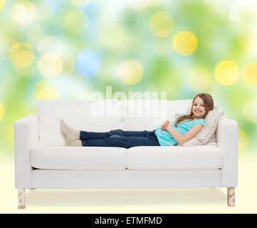 Sorridente bambina sdraiato sul divano Foto Stock
