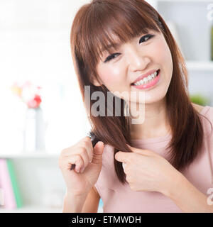 Ritratto di attraente ragazza asiatica pettinare capelli al mattino. Giovane donna in interni stile di vita vita a casa. Foto Stock