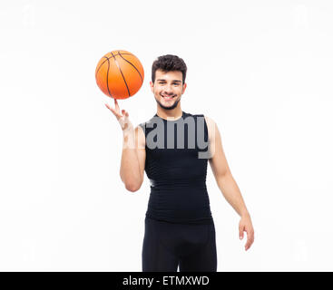 Sorridente giocatore di pallacanestro di sfera di filatura sul suo dito isolato su uno sfondo bianco e guardando la fotocamera Foto Stock