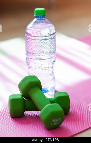 Due manubri con acqua minerale sul materassino yoga, sportivo il concetto di stile di vita Foto Stock