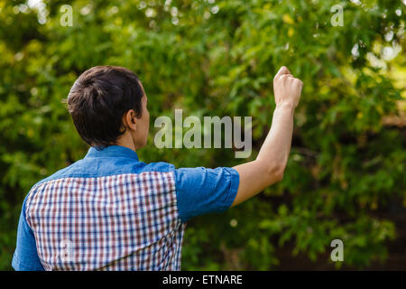 Indietro man mano che scrive in aria su uno sfondo verde street Foto Stock