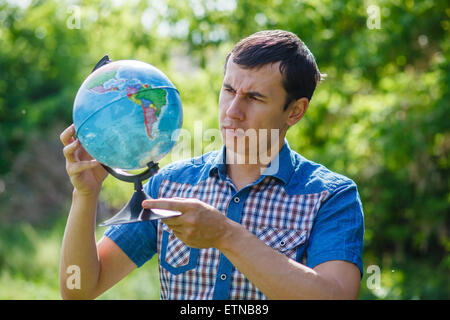 Uomo in strada tenendo un globo su sfondo verde estate Foto Stock