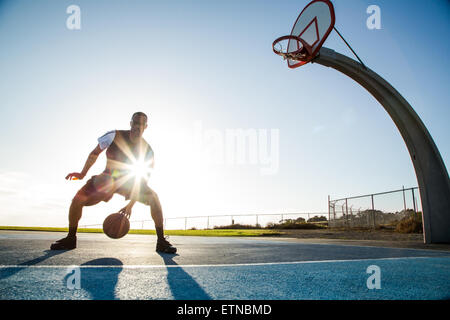 Giovane uomo giocando a basket in un parco di Los Angeles, California, Stati Uniti d'America Foto Stock