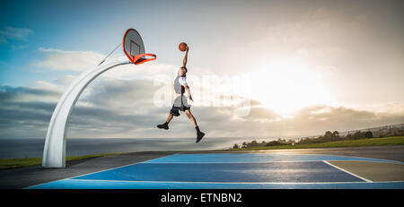 Giovane uomo giocando a basket in un parco di Los Angeles, California, Stati Uniti d'America Foto Stock