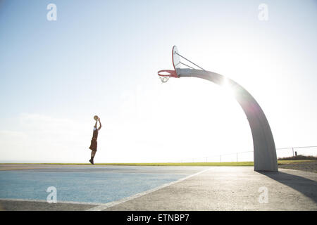 Giovane uomo che gioca a pallacanestro in un parco, Los Angeles, California, Stati Uniti Foto Stock