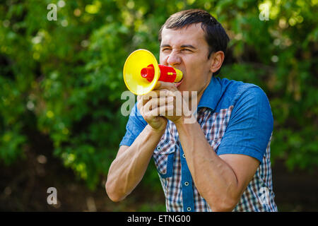 L'uomo della strada tenendo un altoparlante in plastica esclamazioni su verde Foto Stock