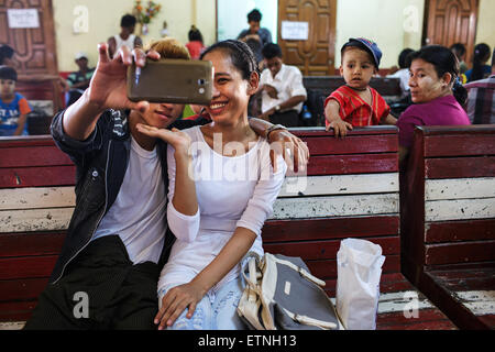 Una giovane coppia di prendere una selfie sul loro smartphone a Yangon, Myanmar (Birmania) Foto Stock