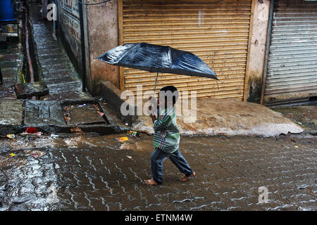 Un giovane ragazzo con ombrello in piogge monsoniche in Mumbai, India Foto Stock